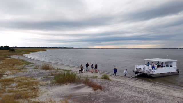 LowCountry Coastal Excursions boat beached on a barrier island near Charleston while guests hunt for shark teeth